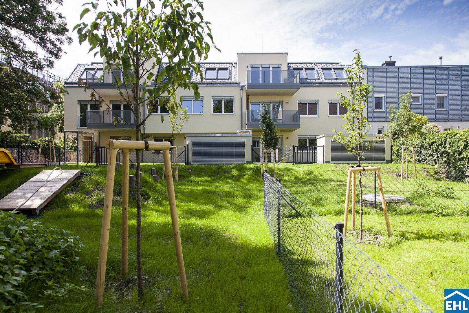 Moderne Wohnanlage mit gepflegter Rasenfläche und privaten Gärten im Außenbereich.