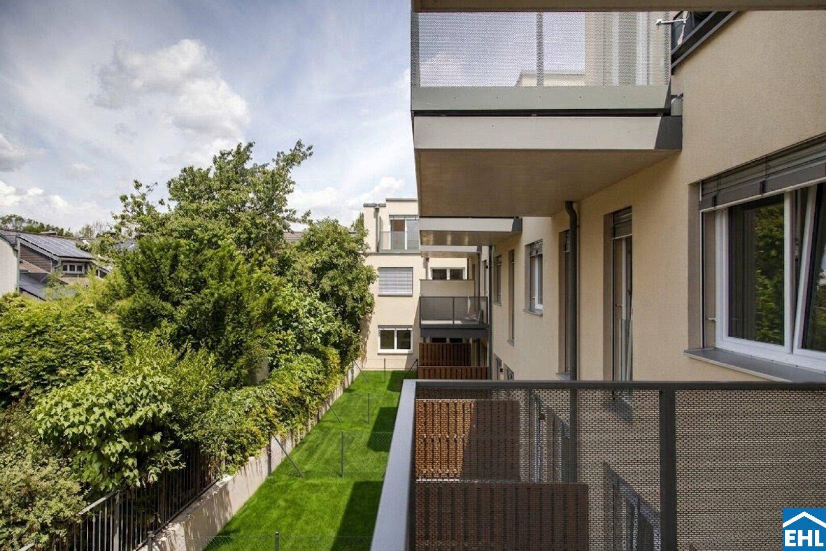 Moderner Balkon mit Blick auf die grüne Umgebung und angrenzende Gebäude.