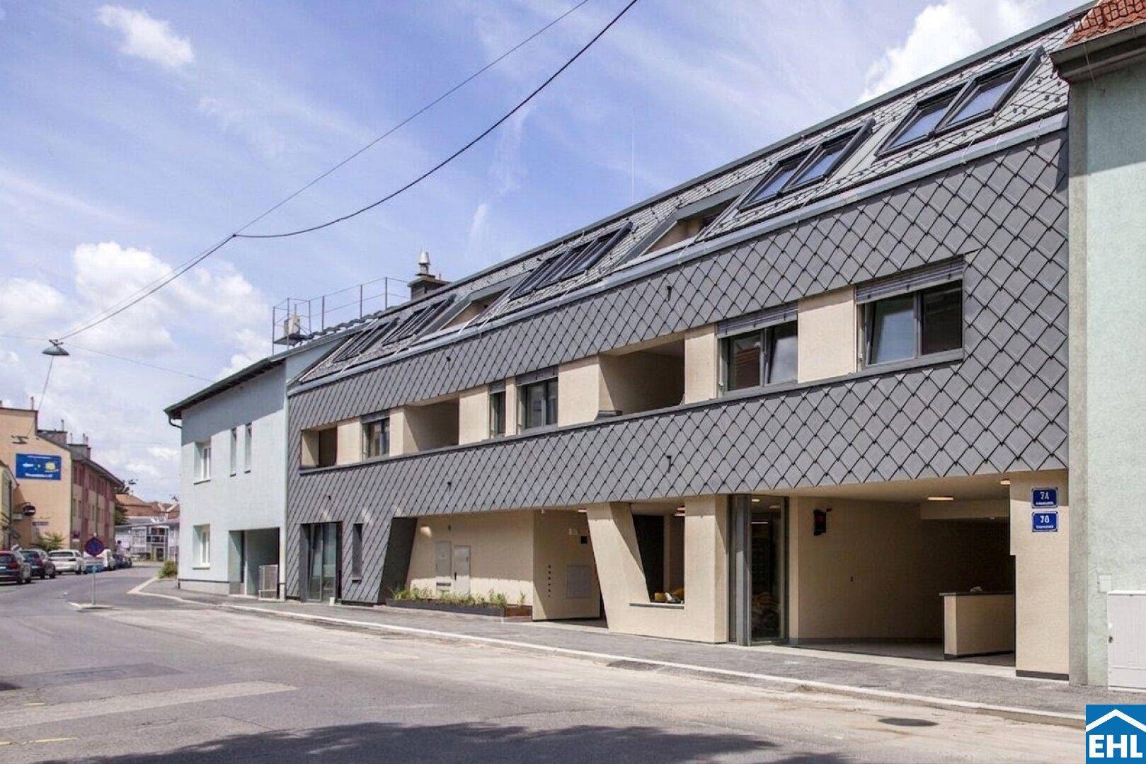 Moderne Straßenfassade des Gebäudes mit Schieferdach und großen Fenstern.