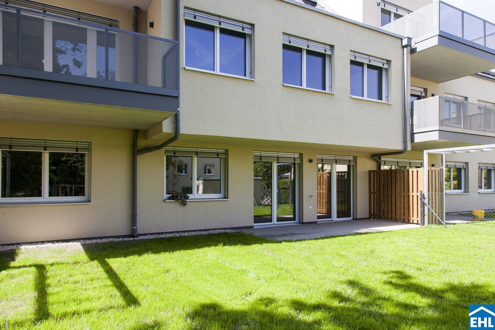 Moderne Erdgeschosswohnung mit direktem Zugang zu einer privaten Terrasse und kleiner Rasenfläche.