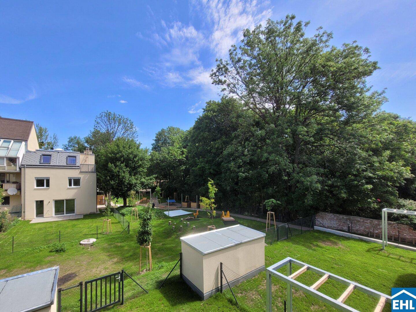 Weitläufiger Gemeinschaftsgarten mit Spielbereich und viel Grün um die moderne Wohnanlage.