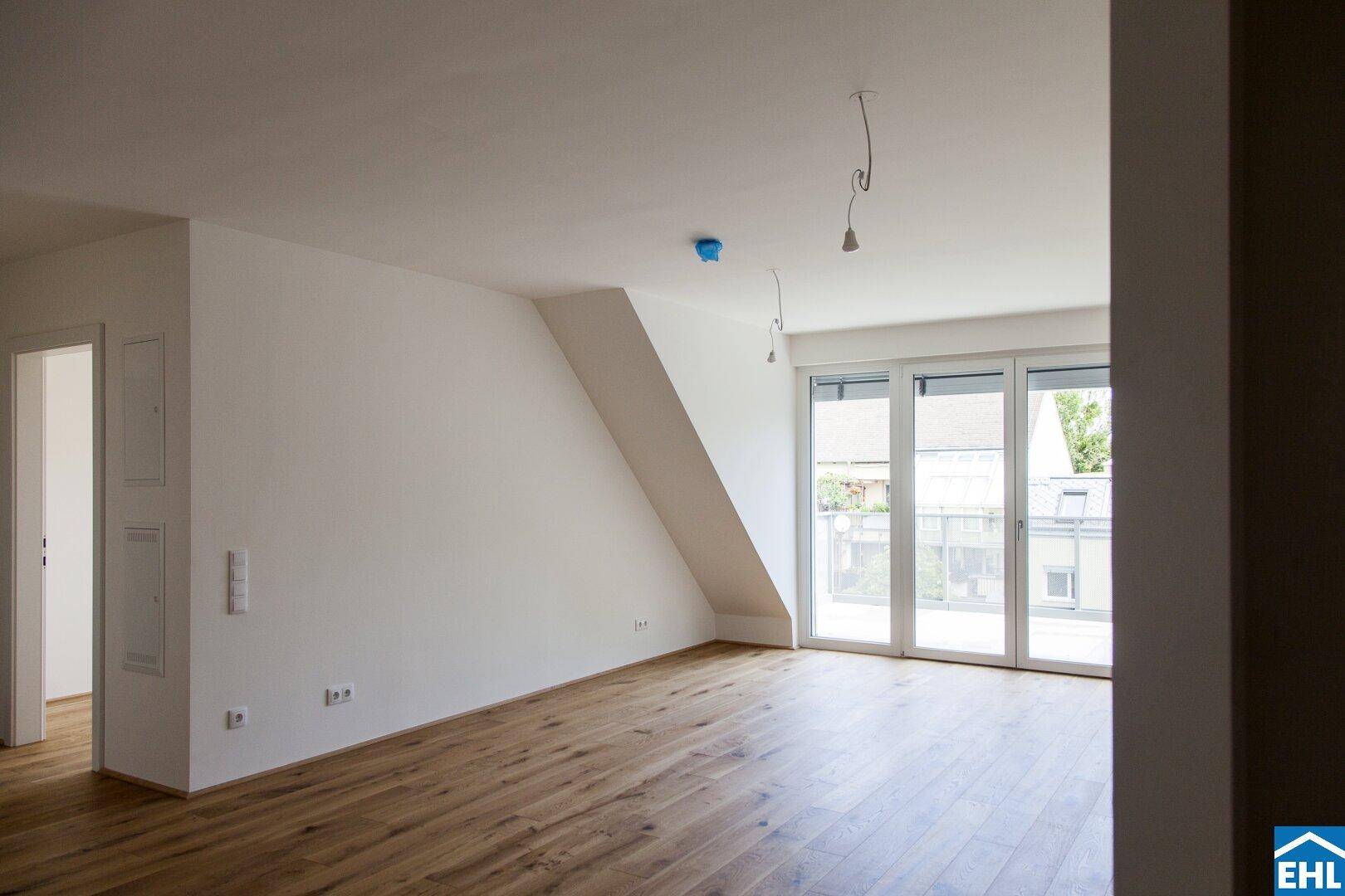 Heller Raum mit Holzboden, Dachschräge und Zugang zu einem Balkon, ideal für individuelle Gestaltung.