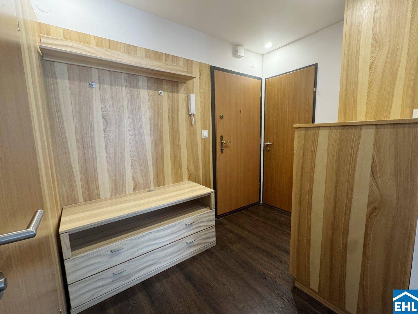 Eingangsbereich mit heller Holzvertäfelung, Garderobe und zwei Eingangstüren.