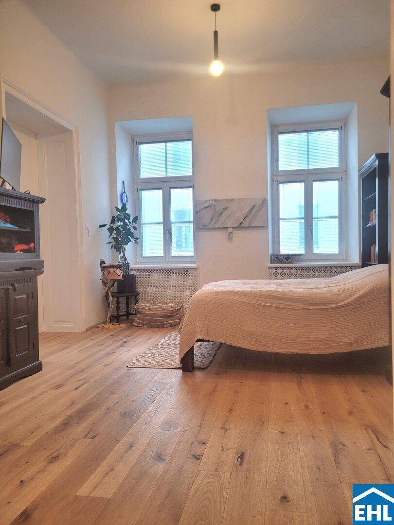 Helles Schlafzimmer mit Holzboden, großen Fenstern und einem bequemen Bett.