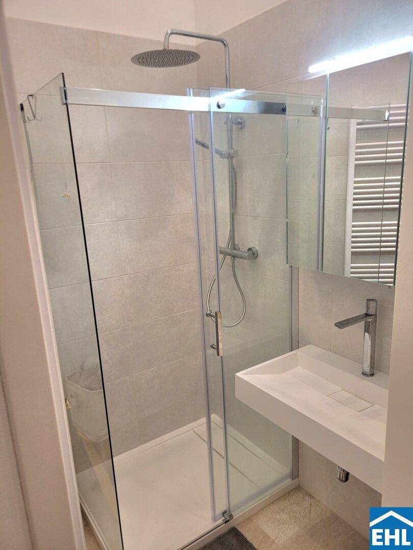 Modernes Badezimmer mit begehbarer Dusche, Regenbrause und beheiztem Handtuchhalter.