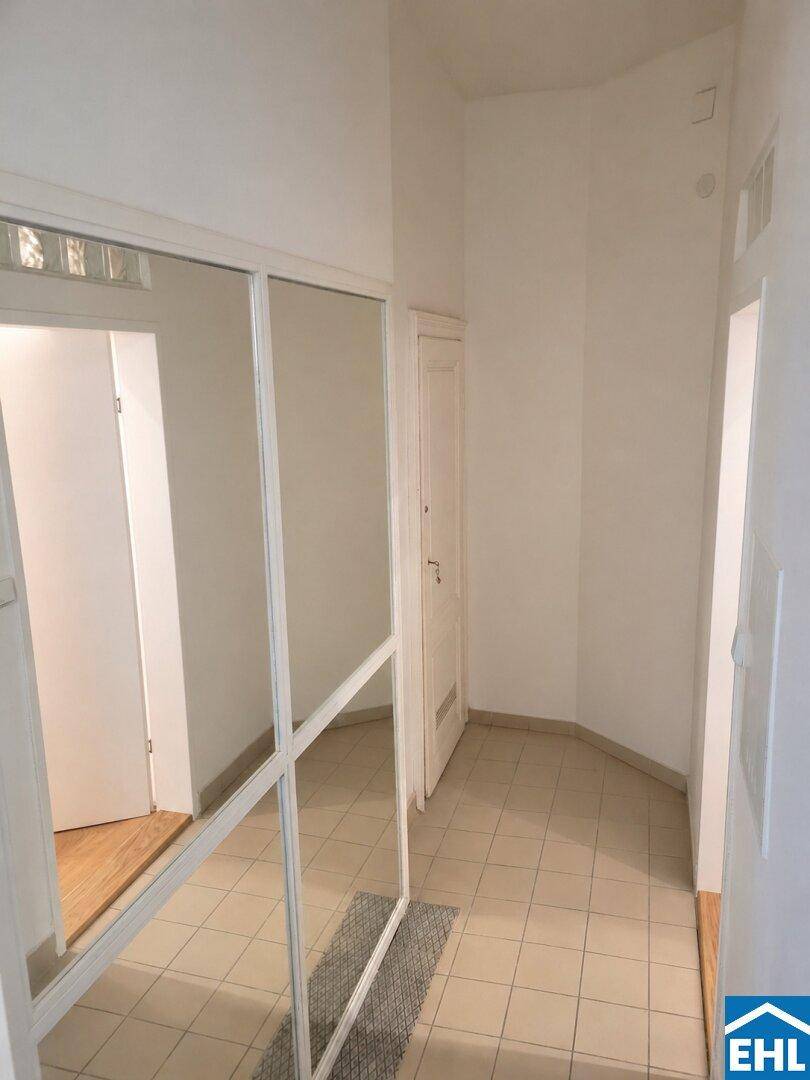Heller Flur mit Fliesenboden und einem großen Spiegel, der den Raum optisch erweitert.