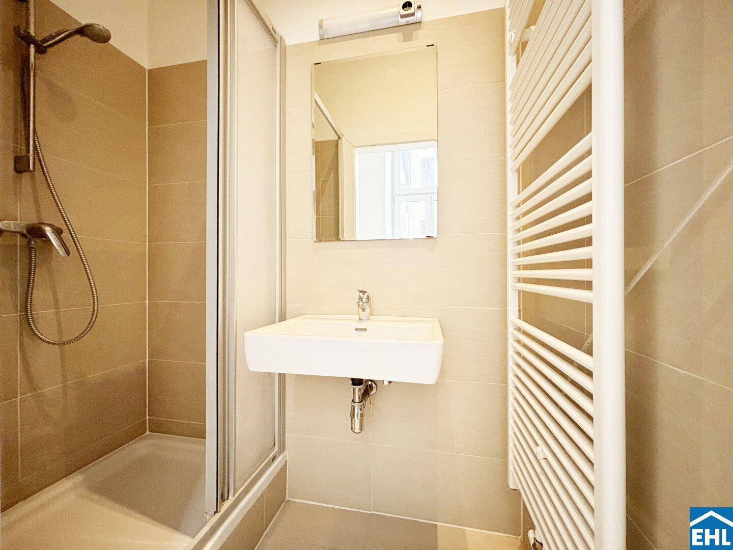 Modernes Badezimmer mit Duschkabine, Waschbecken und beheiztem Handtuchhalter.
