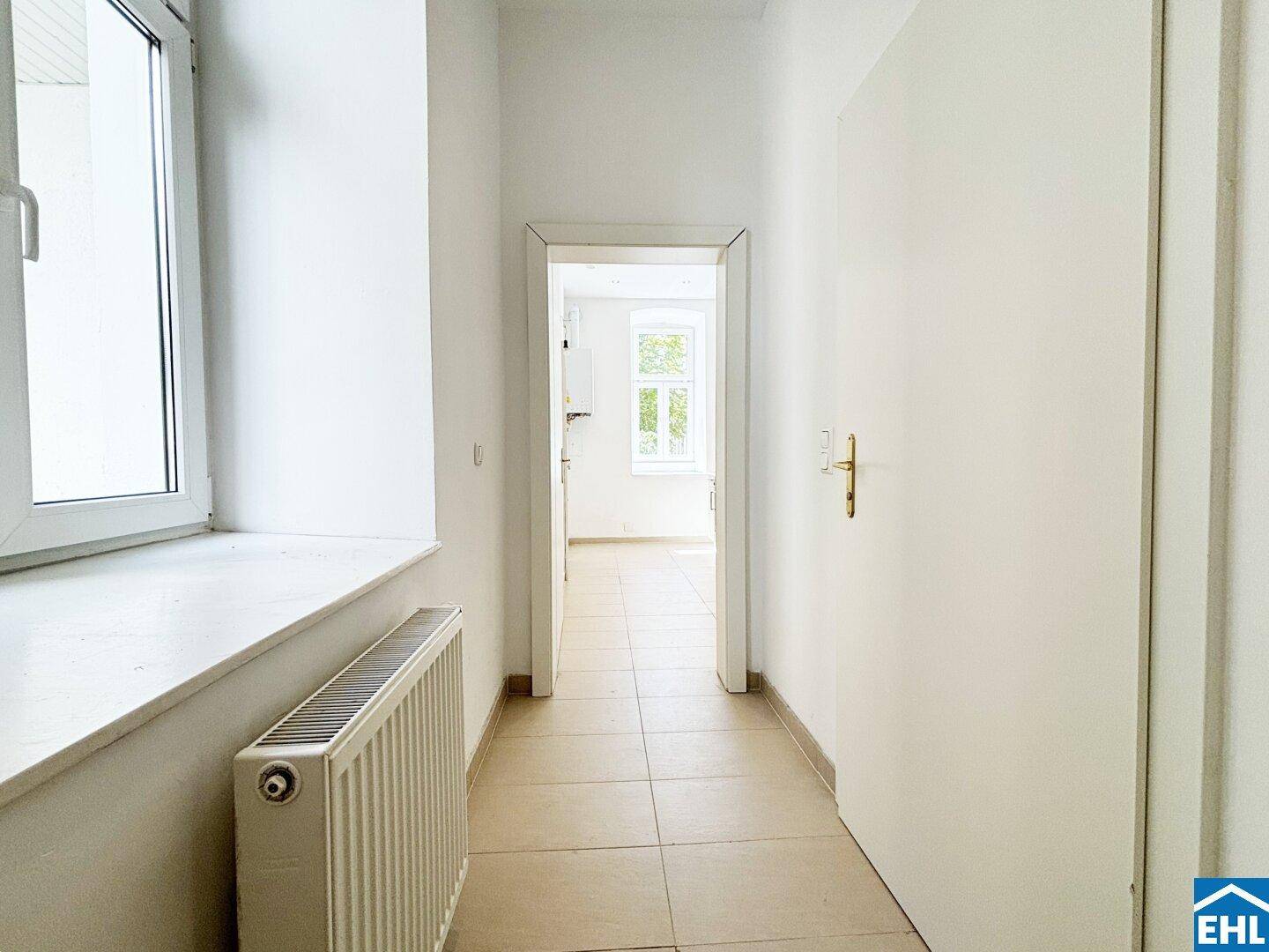 Heller Flur mit Fliesenboden und Zugang zu weiteren Räumen der Wohnung.