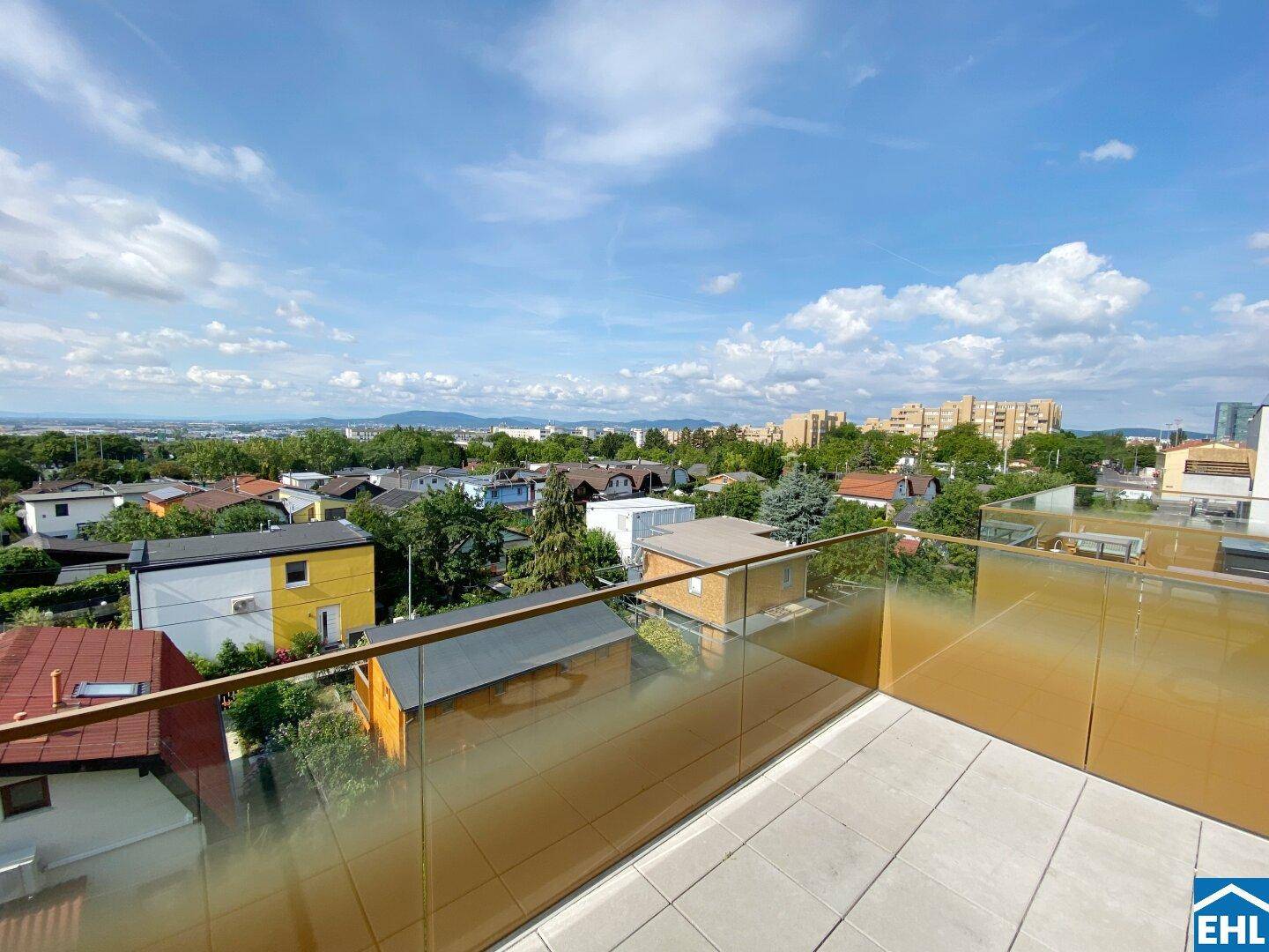 Sonniger Balkon mit moderner Glasbrüstung und Panoramablick über die Stadt und die Umgebung.