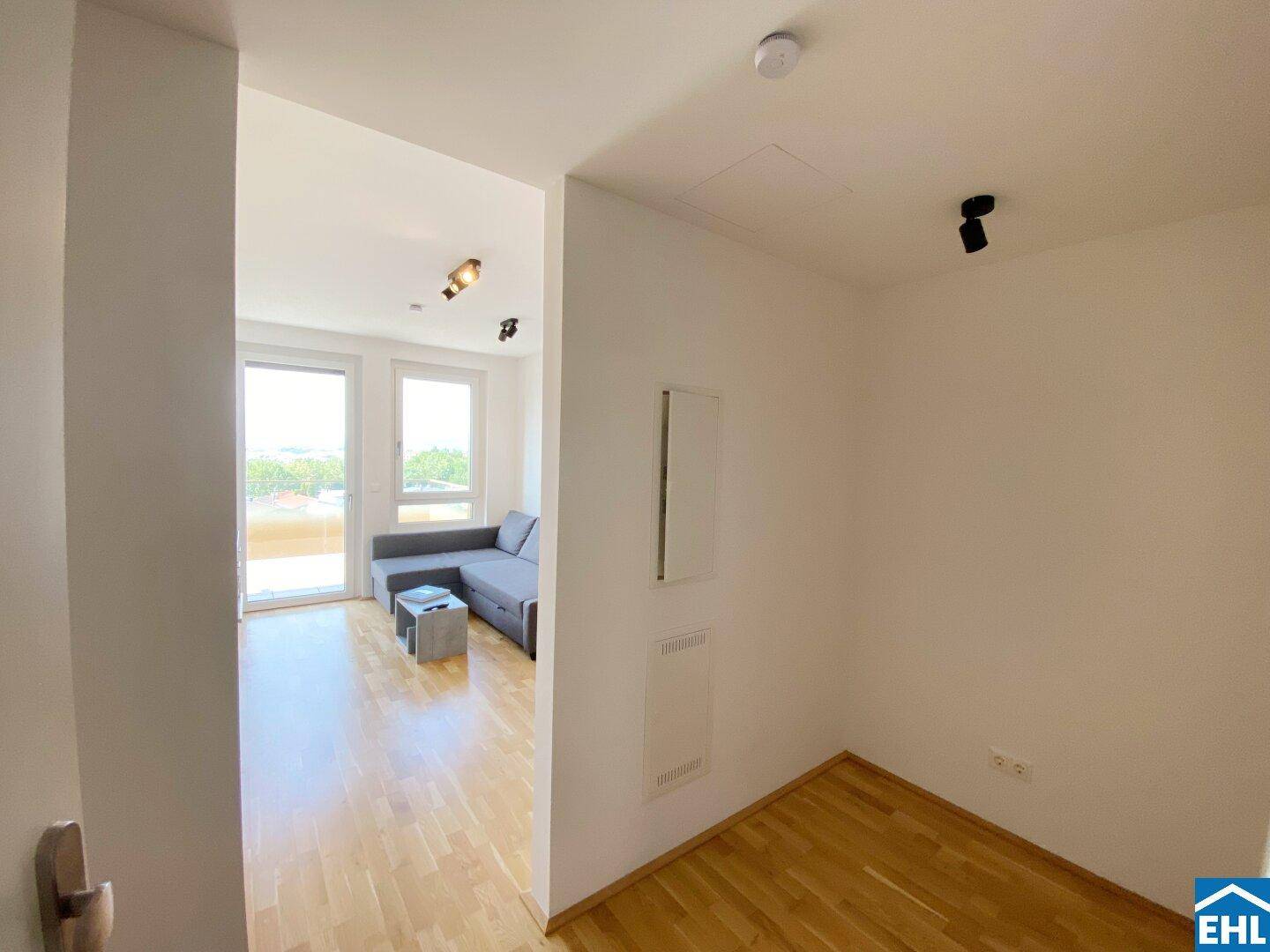 Heller Flur mit Holzfußboden, der offen in den modernen Wohnbereich übergeht.