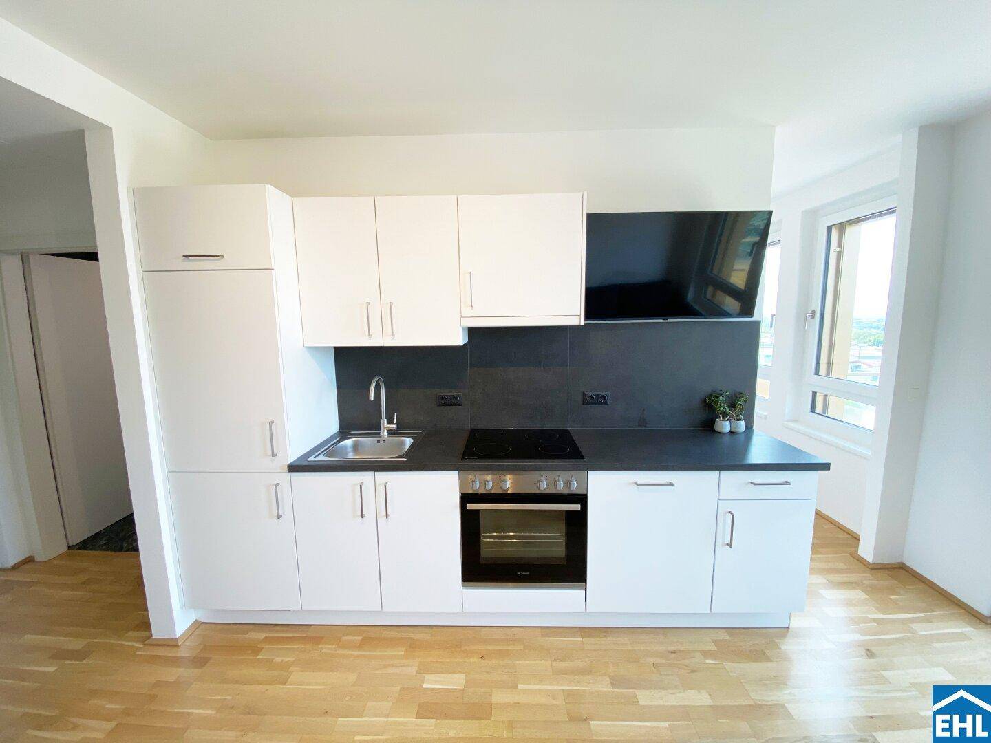 Moderne, kompakte Einbauküche mit weißen Fronten, Induktionskochfeld und integriertem Backofen.