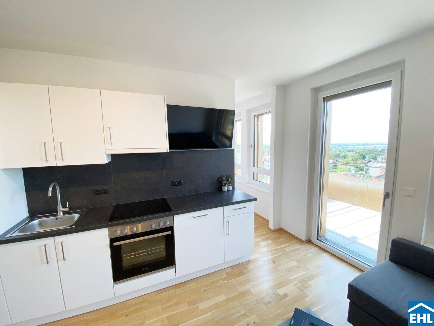 Helle Küchenzeile mit Zugang zum Balkon und weitem Blick auf die umliegende Landschaft.