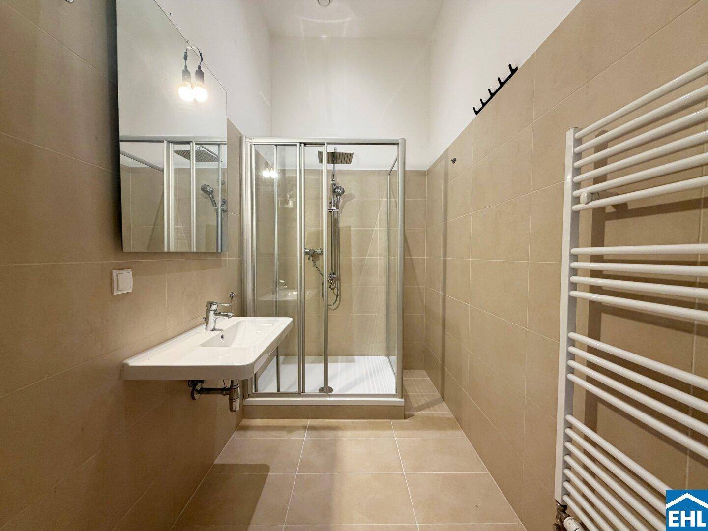 Modernes Badezimmer mit beigefarbenen Fliesen, Duschkabine und beheiztem Handtuchhalter.