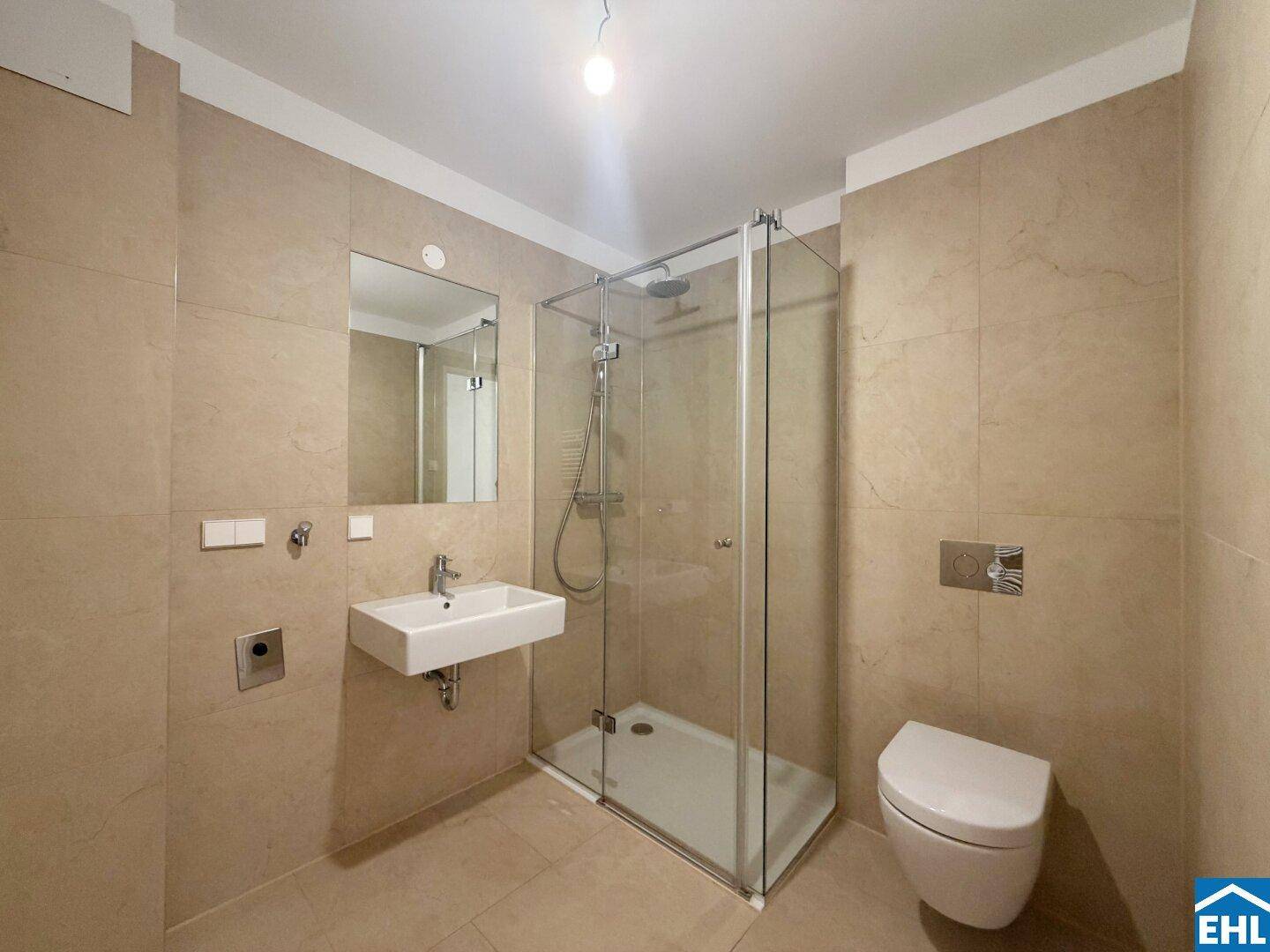 Modernes Badezimmer mit beigefarbenen Fliesen, Duschkabine und wandhängendem WC.