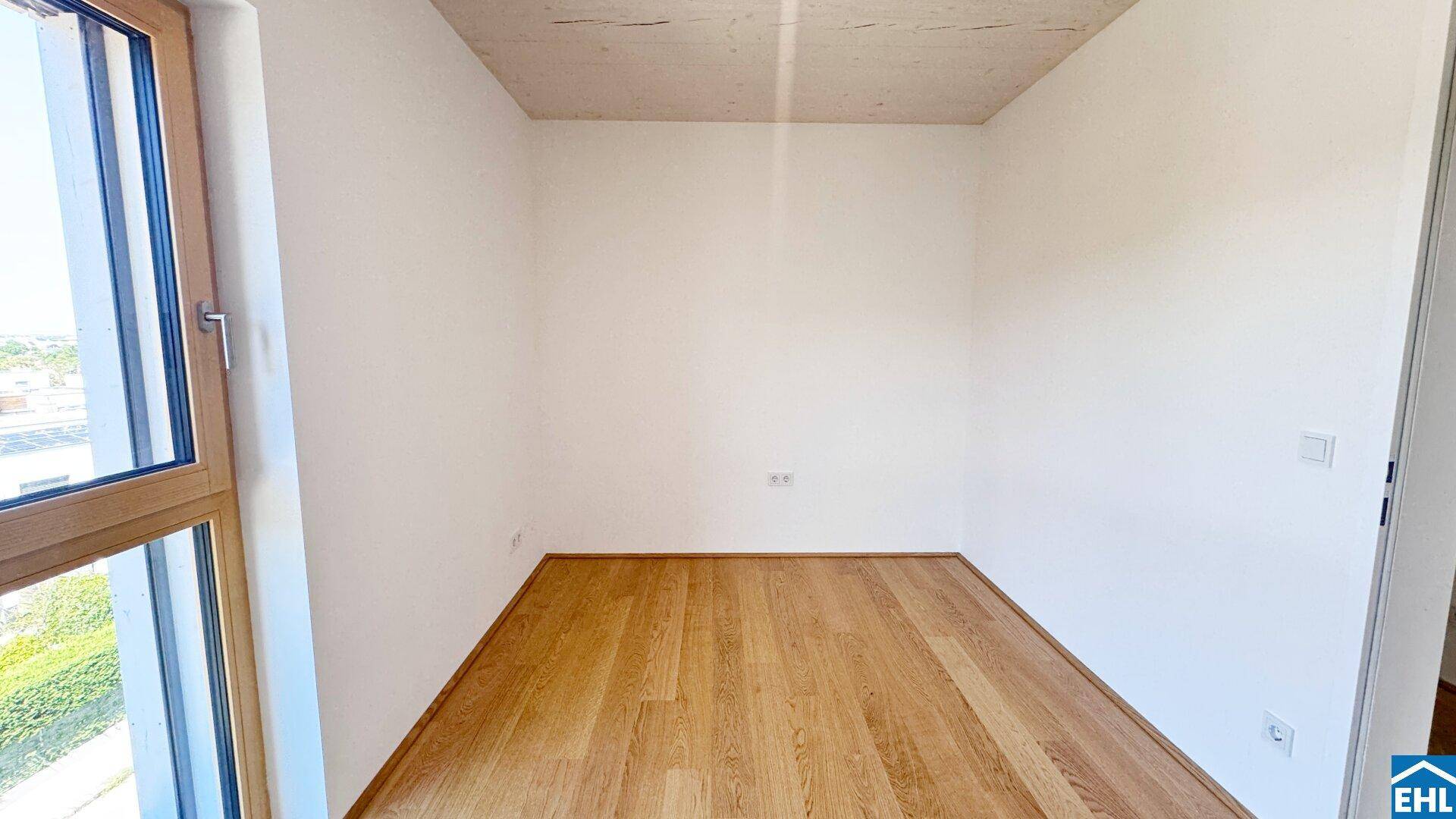Kleiner, heller Raum mit Holzboden und einem Fenster, ideal als Schlaf- oder Arbeitszimmer.