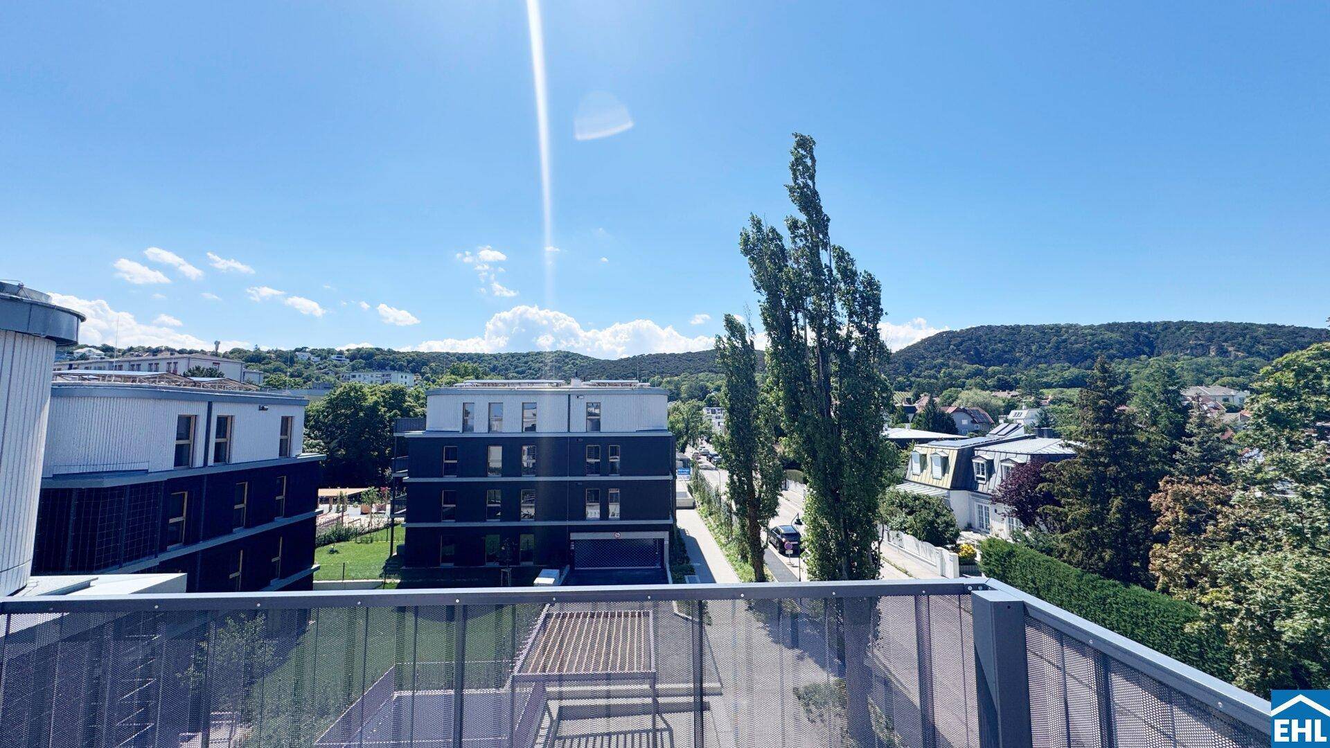 Weitläufiger Blick auf moderne Gebäude und die grüne Umgebung unter strahlend blauem Himmel.