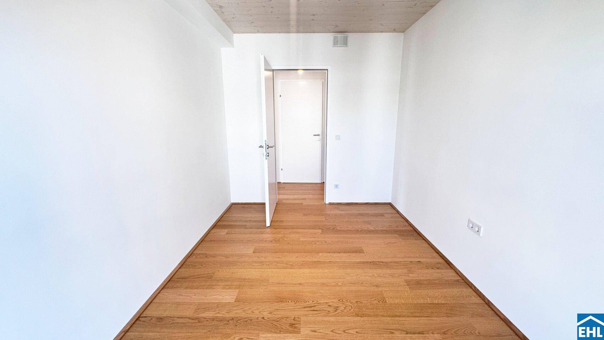 Leeres Schlafzimmer mit hellem Holzboden und weiß gestrichenen Wänden, bereit zur individuellen Gestaltung.