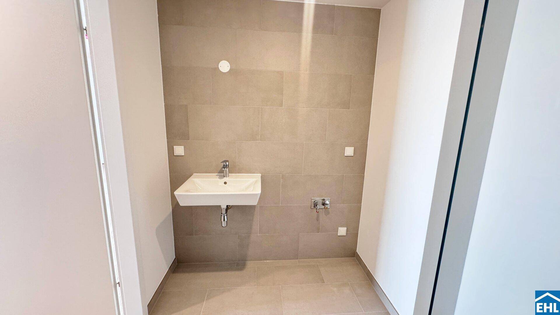 Kleines Badezimmer mit modernem Waschbecken und hellen Fliesen an Wänden und Boden.