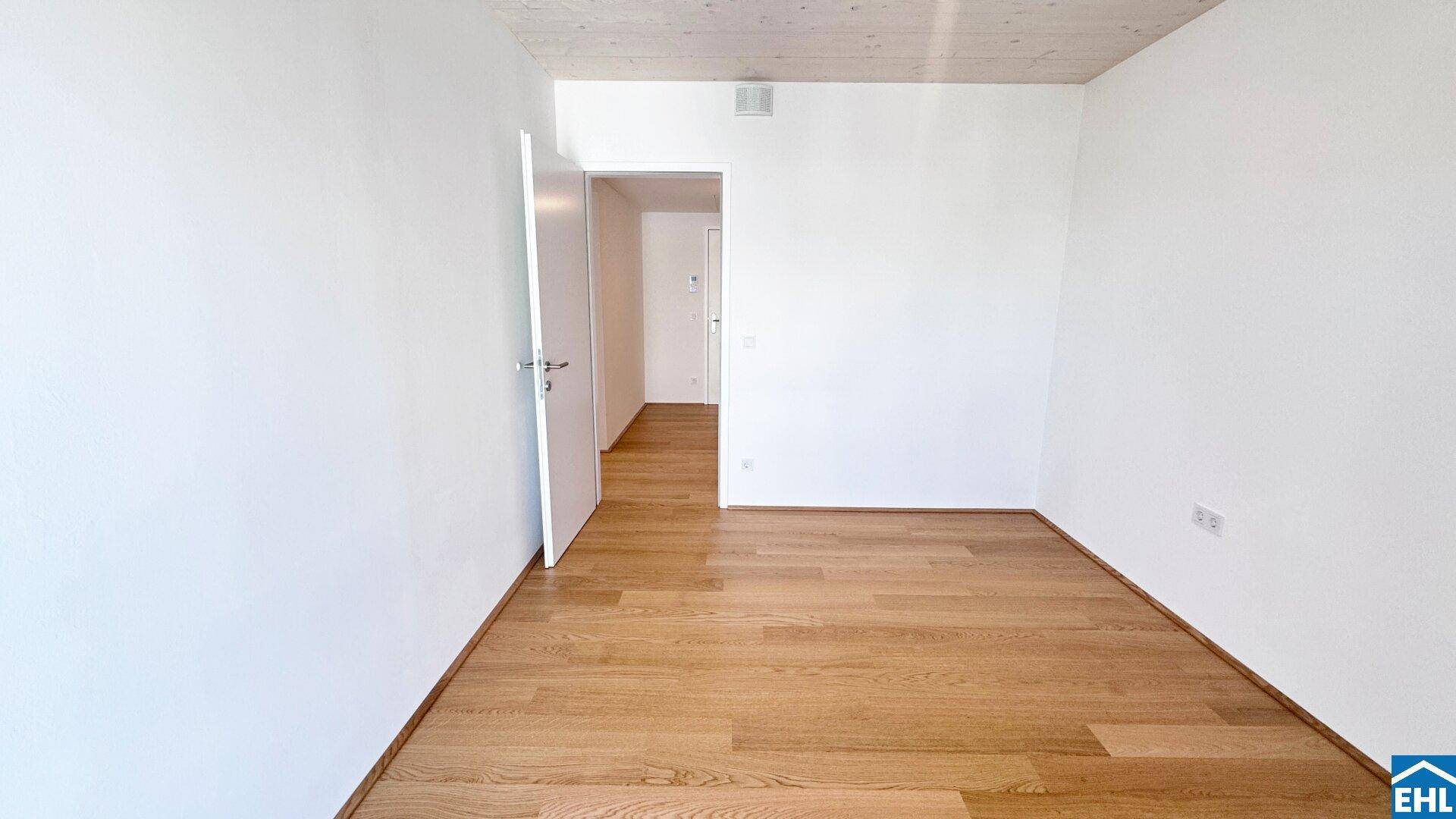 Leeres Schlafzimmer mit hellem Holzboden und weiß gestrichenen Wänden, bereit zur individuellen Gestaltung.