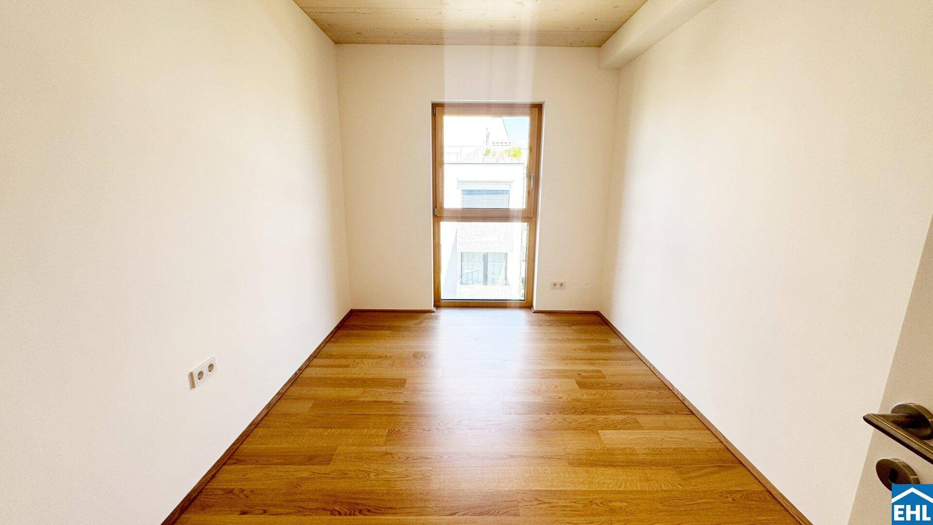 Helles Schlafzimmer mit Holzboden und einem Fenster, das viel Tageslicht in den Raum lässt.
