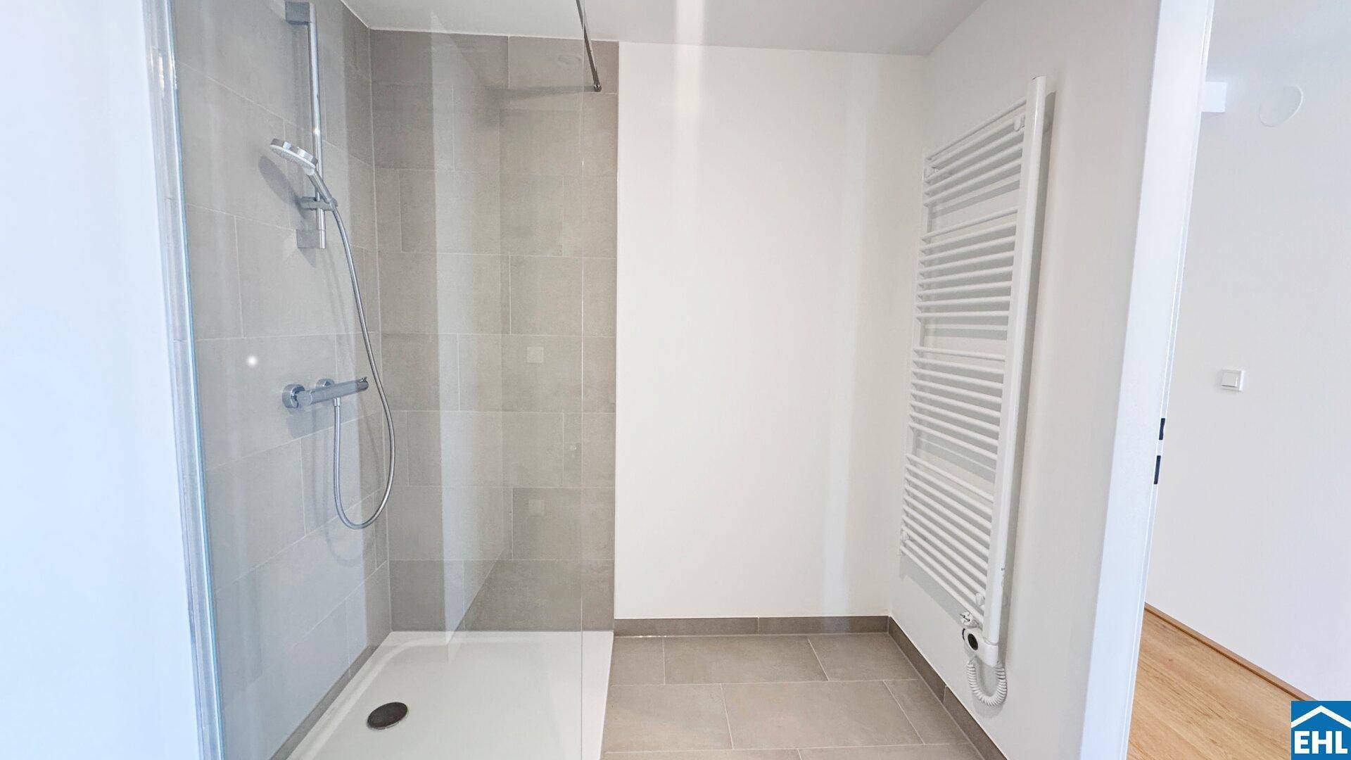 Modernes Badezimmer mit ebenerdiger Dusche, Fliesenboden und praktischem Handtuchheizkörper.