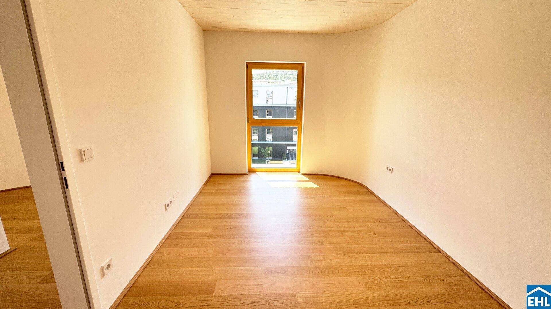 Leeres Zimmer mit Holzboden und einem Fenster, bereit für individuelle Gestaltung und Nutzung.