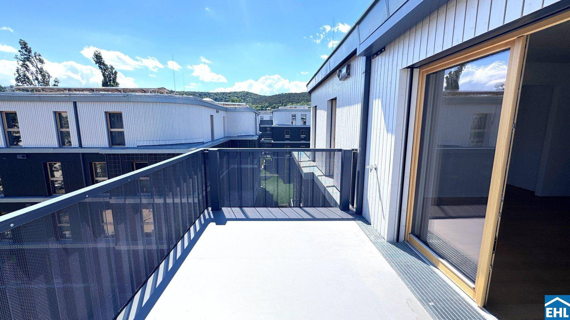 Balkon mit moderner Architektur und Blick auf andere Gebäude und den Himmel.