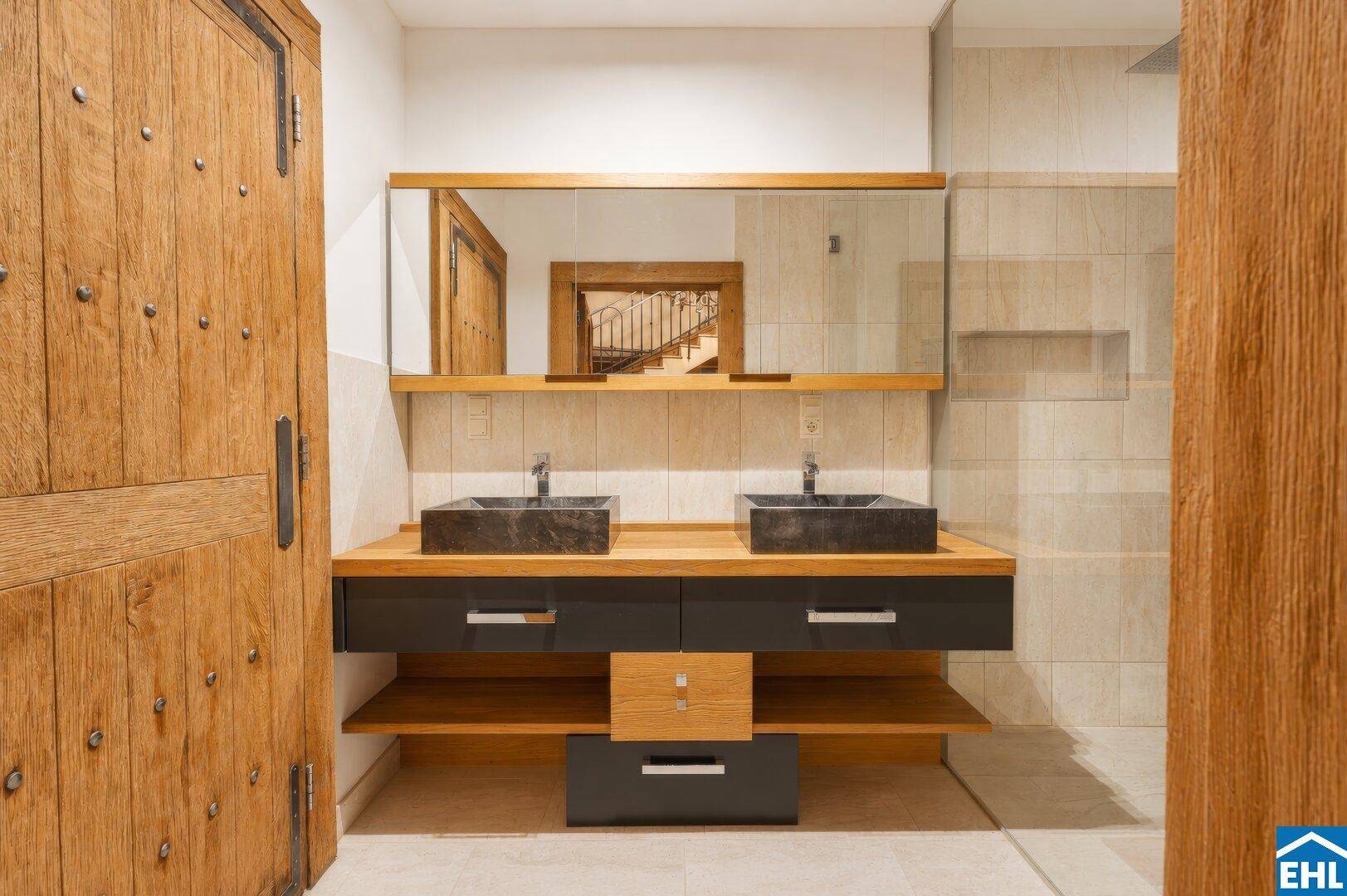 Modernes Badezimmer mit Doppelwaschbecken, Holzdetails und begehbarer Dusche.