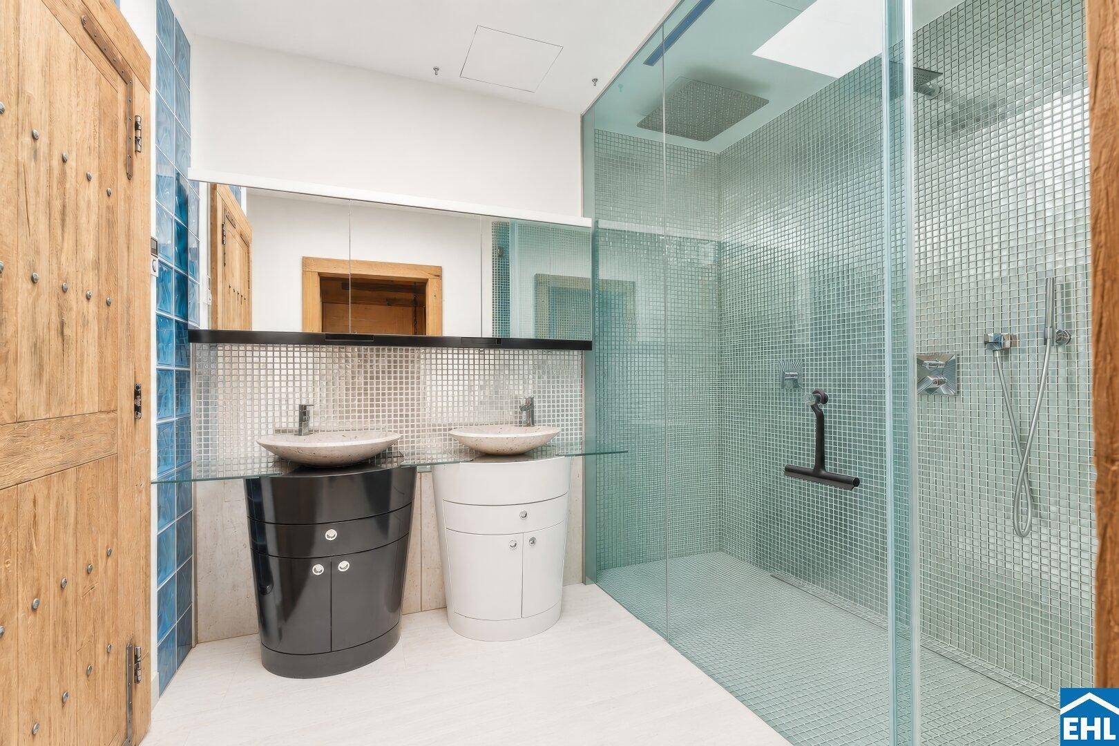 Modernes Badezimmer mit zwei Waschbecken, großer begehbarer Dusche und blauen Mosaikfliesen.