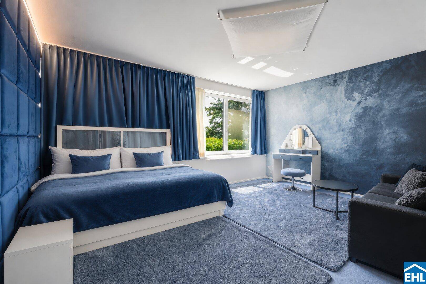 Gemütliches Schlafzimmer in Blautönen mit großem Bett, Teppichboden und Schminktisch.