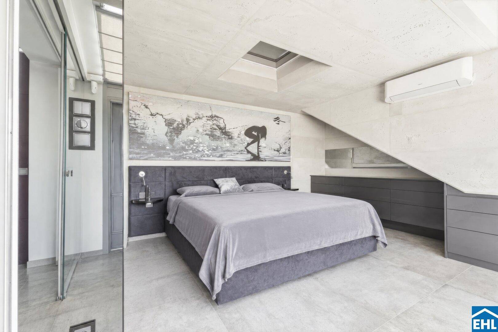 Modernes Schlafzimmer mit großem Bett, grauen Fliesen und Oberlicht für natürliches Licht.