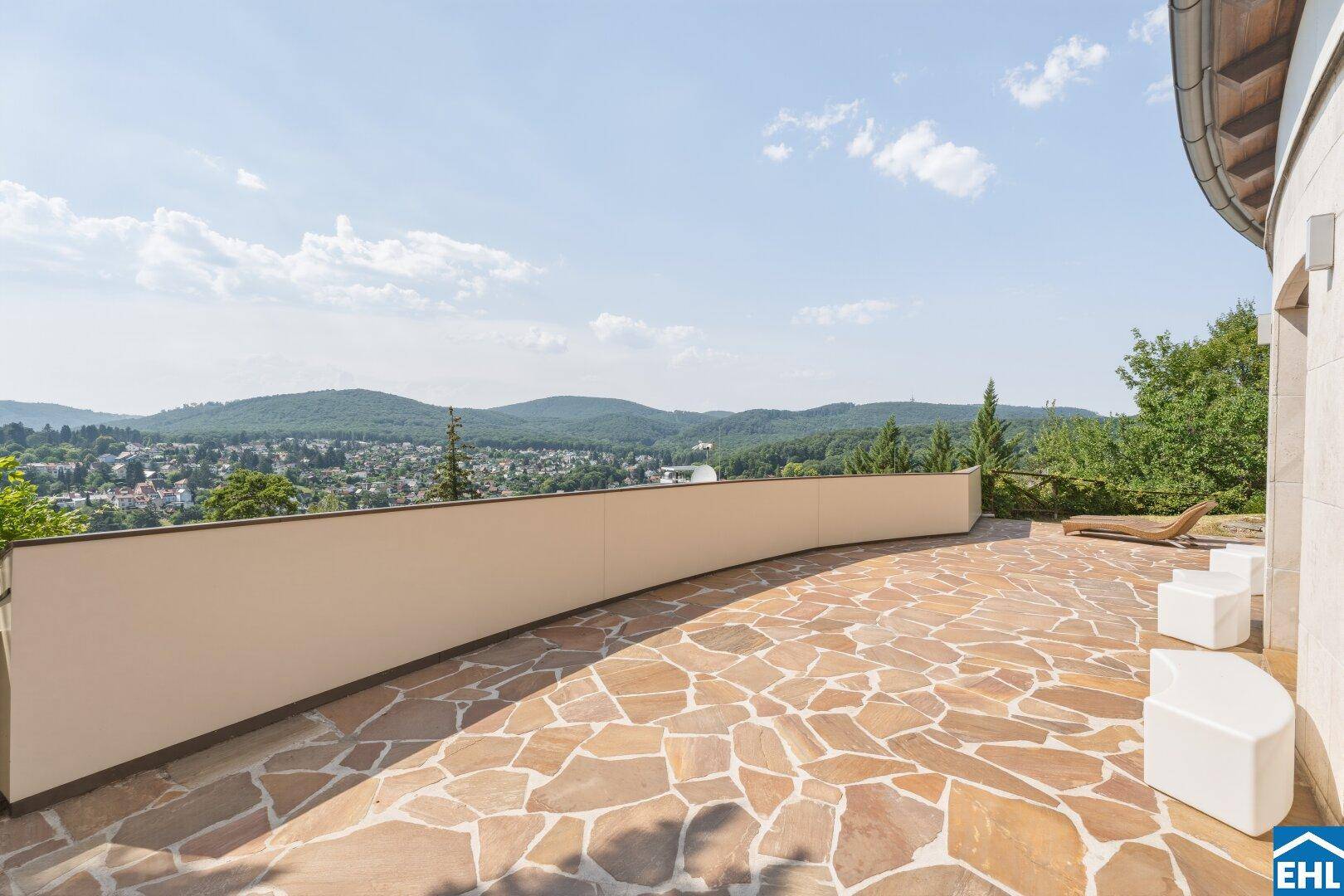 Geräumige Terrasse mit weitem Blick über die Landschaft und die Dächer der umliegenden Häuser.