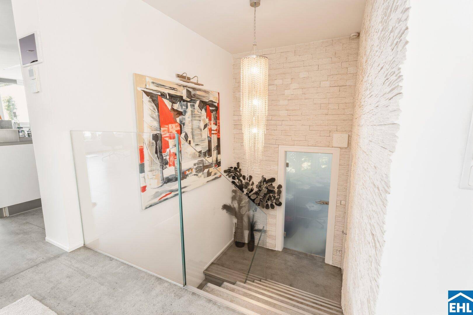 Eingangsbereich mit Treppe, Kronleuchter und dekorativer Steinwand.