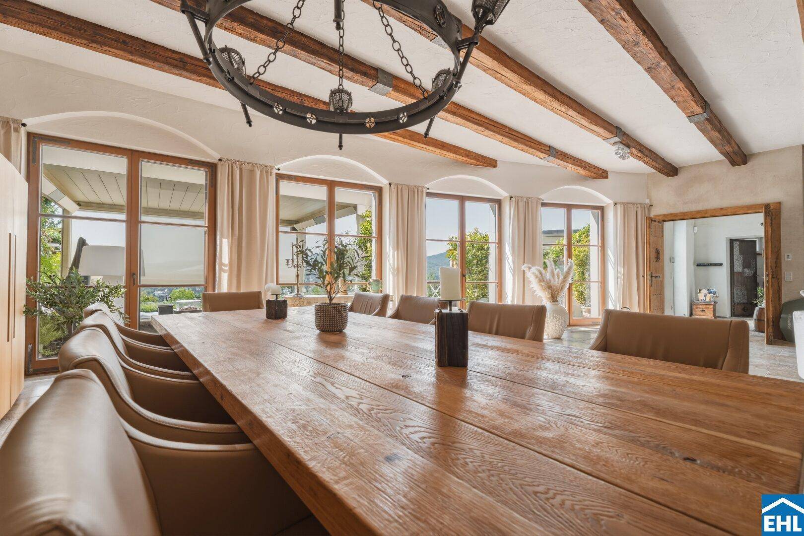 Geräumiger Essbereich mit Holztisch, großen Fenstern und Zugang zum Außenbereich.