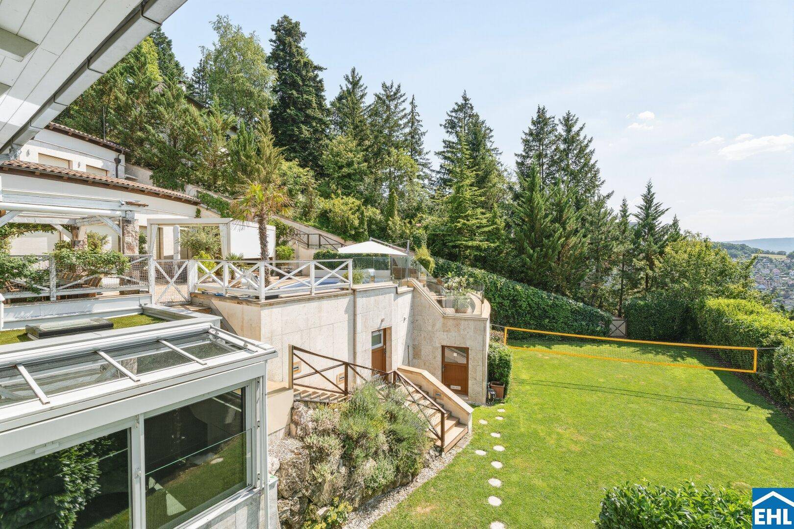 Terrassierter Gartenbereich mit Rasenfläche, Treppen und Blick auf die umliegende Natur.