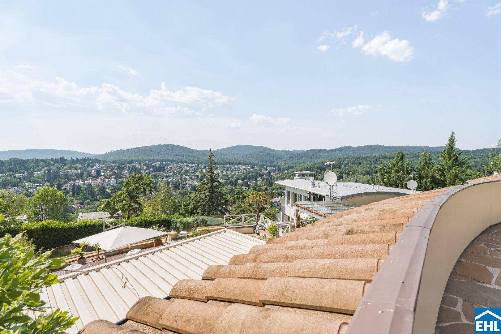 Blick von einer oberen Terrasse über die Ziegeldächer und die weite, grüne Landschaft.