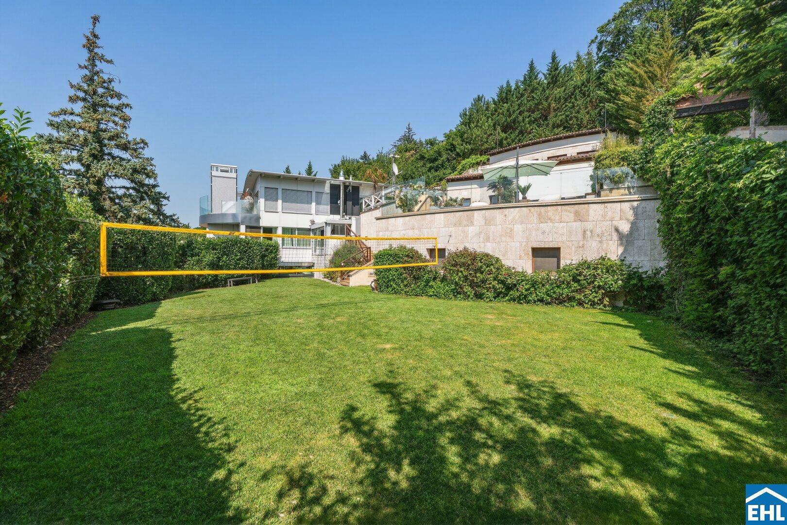 Große Rasenfläche im Garten mit Volleyballnetz, ideal für sportliche Aktivitäten im Freien.