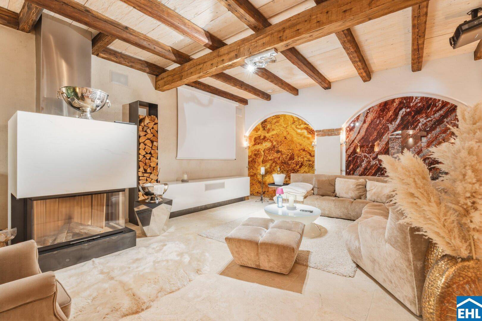 Luxuriöser Wohnbereich mit Kamin, Holzbalken und gemütlicher Sofalandschaft.