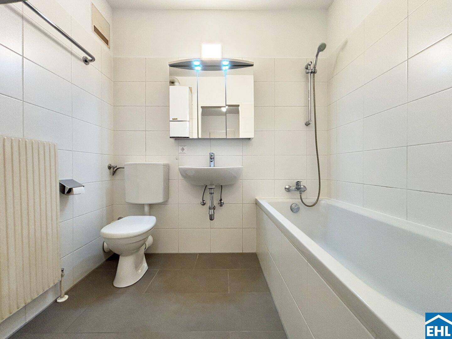 Funktionales Badezimmer mit Badewanne, WC, Waschbecken und Wandfliesen.