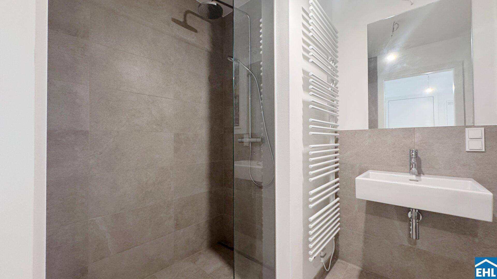 Modernes Badezimmer mit begehbarer Dusche, Wandwaschbecken und beheiztem Handtuchhalter.