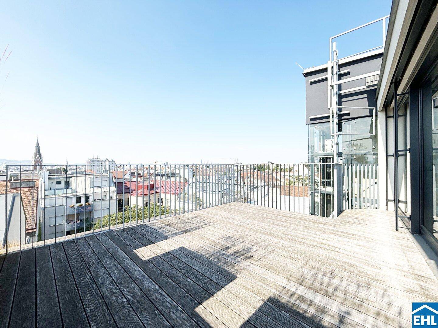 Geräumige Dachterrasse mit Holzboden und weitem Blick über die Dächer der Stadt.