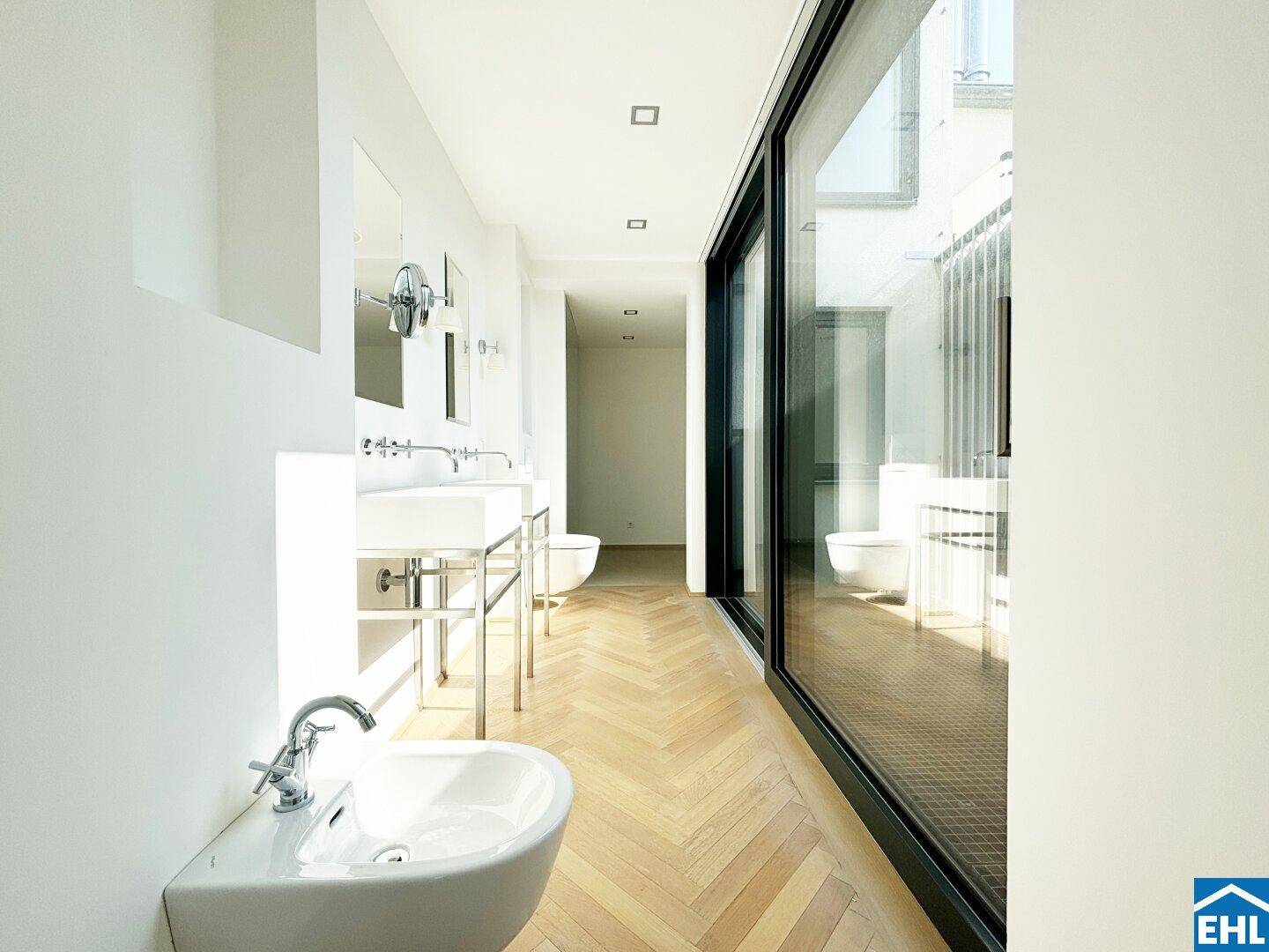 Modernes Badezimmer mit mehreren Waschbecken, Bidet und großen Fenstern für viel Licht.