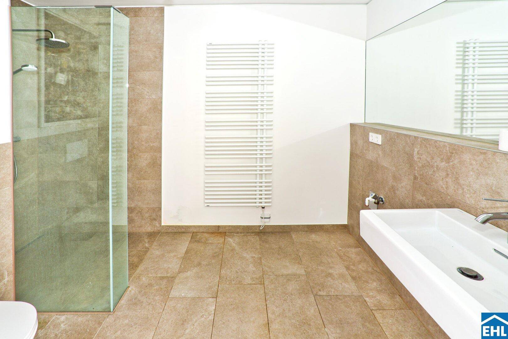 Modernes Badezimmer mit beigefarbenen Fliesen, ebenerdiger Dusche und beheiztem Handtuchhalter.