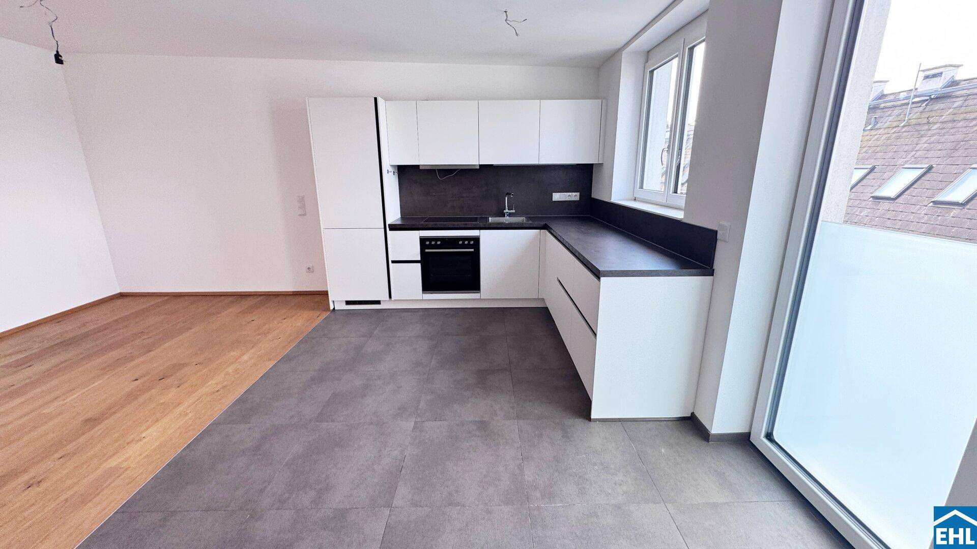 Moderne Küche im offenen Wohnbereich mit weißen Schränken und Zugang nach draußen.