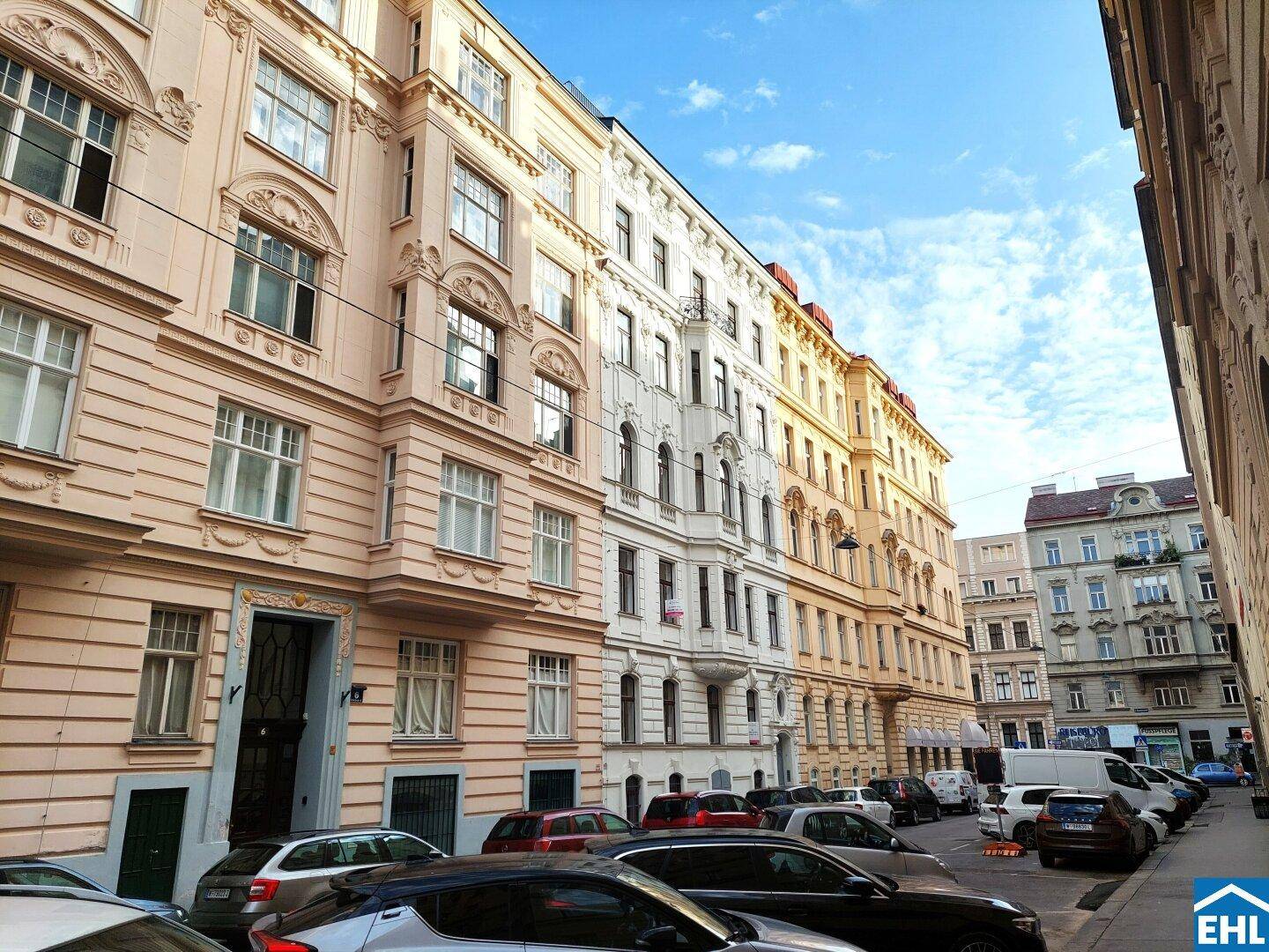 Historische Wohngebäude mit klassischer Architektur und geparkten Autos entlang der Straße.