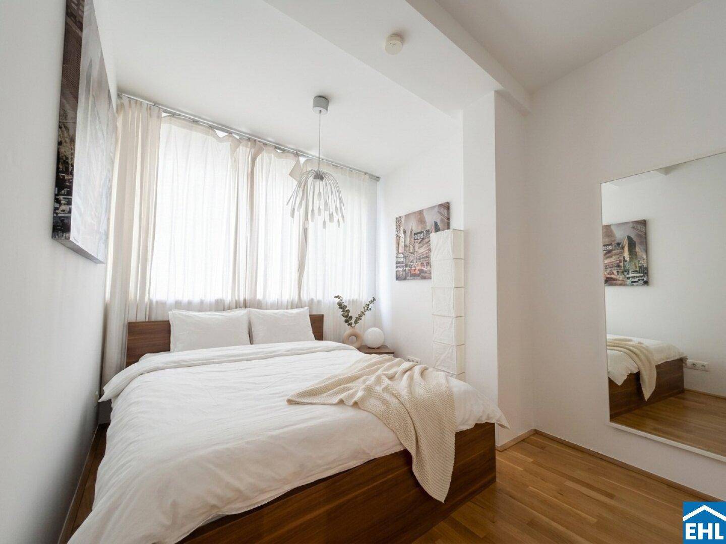 Helles Schlafzimmer mit Holzbett, großen Fenstern und minimalistischer Einrichtung.