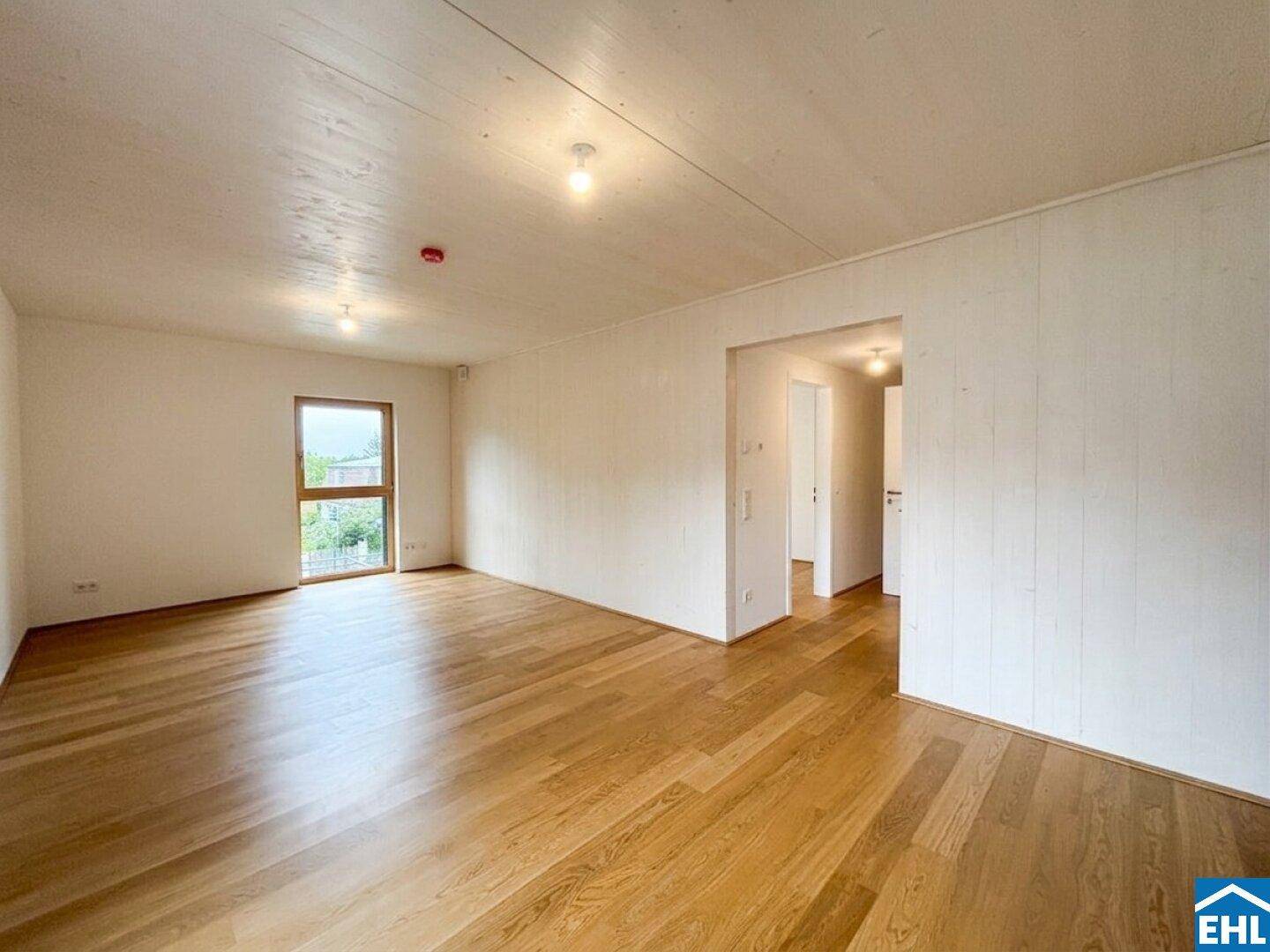 Heller Raum mit Holzboden und Zugang zu einem Flur, ideal als Wohn- oder Schlafzimmer.