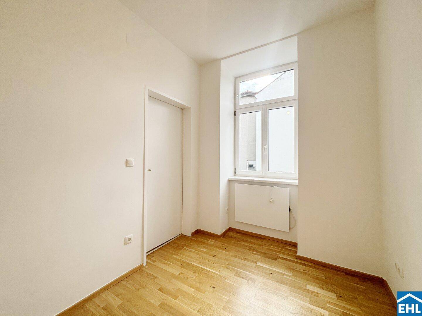 Ruhiges Zimmer mit Holzboden und einem Fenster, geeignet als Schlaf- oder Arbeitszimmer.