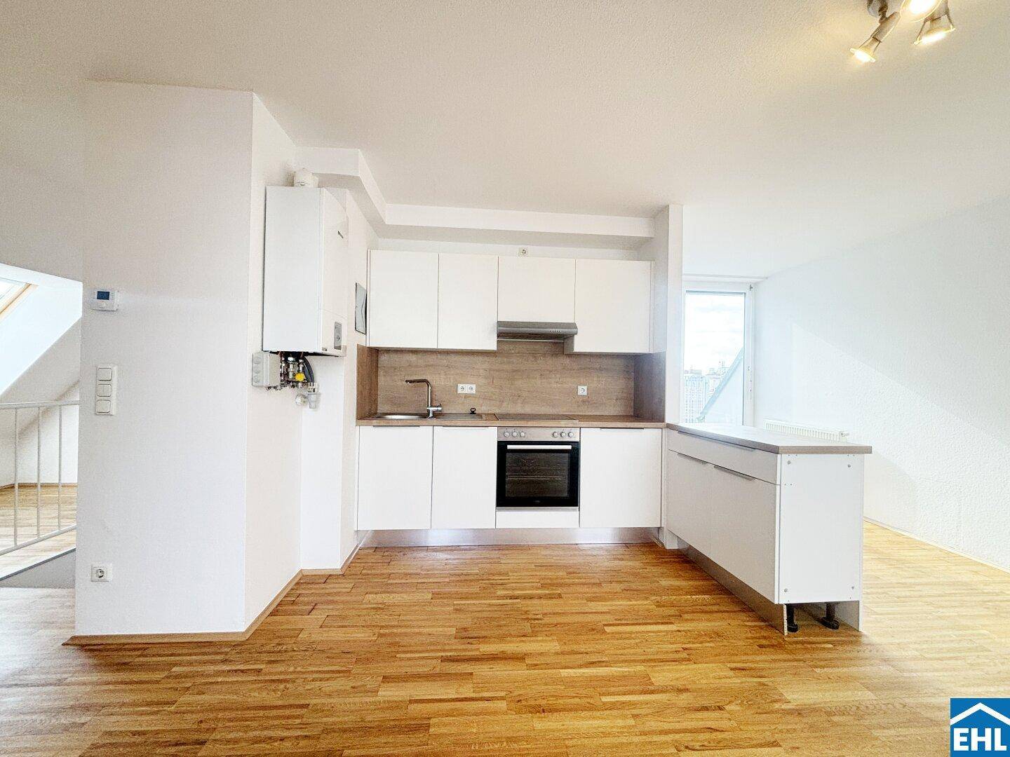 Funktionale Einbauküche mit weißen Schränken, Holz-Arbeitsplatte und integriertem Backofen.