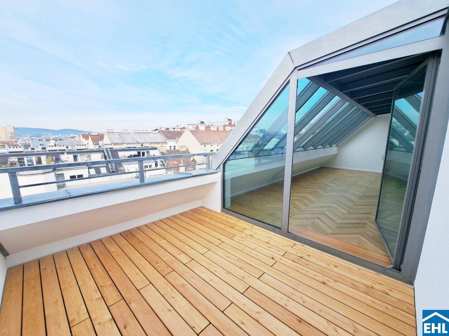 Geräumige Dachterrasse mit Holzboden und weitem Stadtblick, verbunden mit einem lichtdurchfluteten Innenraum.
